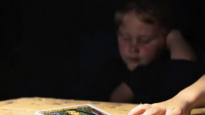 Расклад Таро на одну карту на детей: карта Жрица лежит на столе, рядом детская рука, символ ненавязчивого присутствия